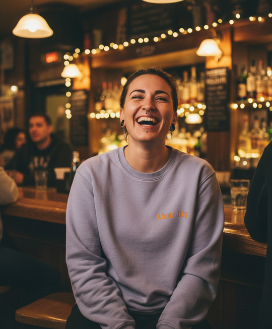 Woman laughing in a bar with warm lighting and shelves of bottles in the background