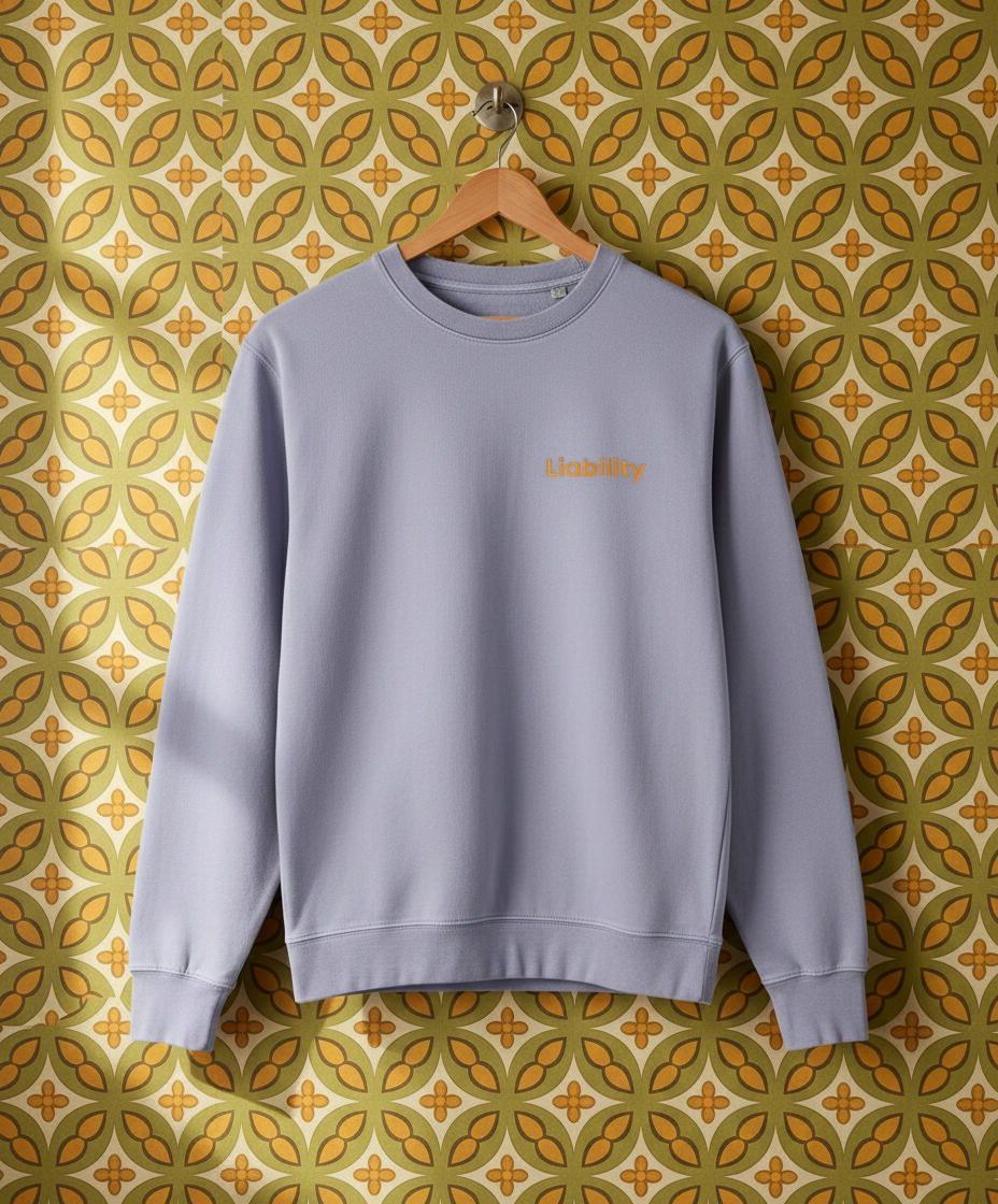 Lilac sweatshirt with text on a hanger against a patterned wall.