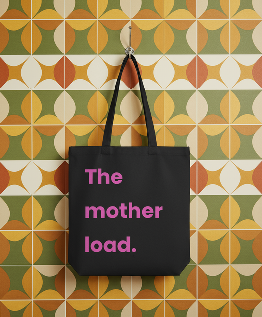 Black tote bag with 'The mother load.' text on a patterned wall background
