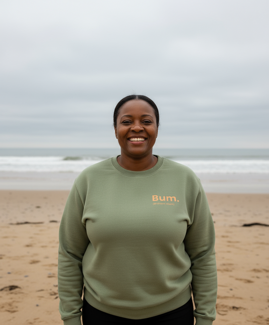 Person wearing a green sweatshirt with 'Bum' logo on a beach