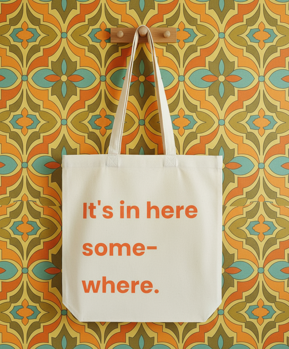 Tote bag with text 'It's in here somewhere' on a patterned wall.