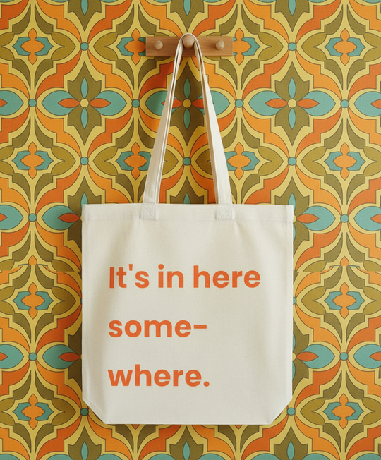 Tote bag with text 'It's in here somewhere' on a patterned wall.