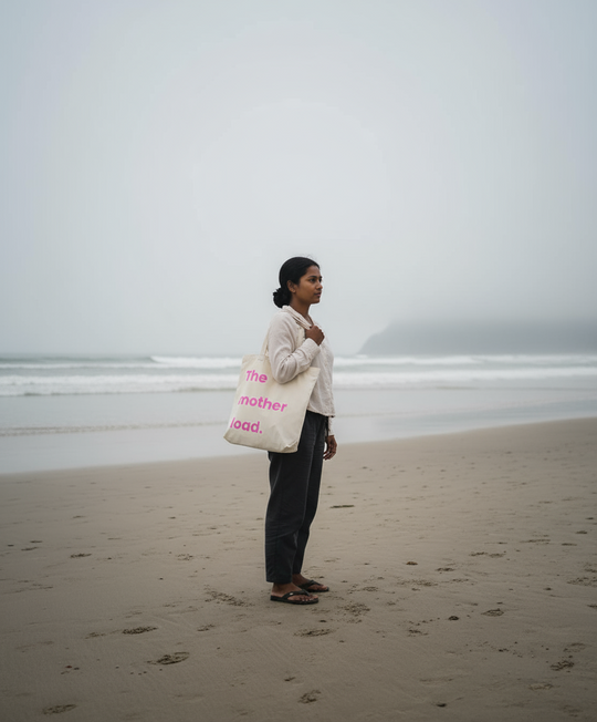 Person holding a tote bag on a beach with a foggy background