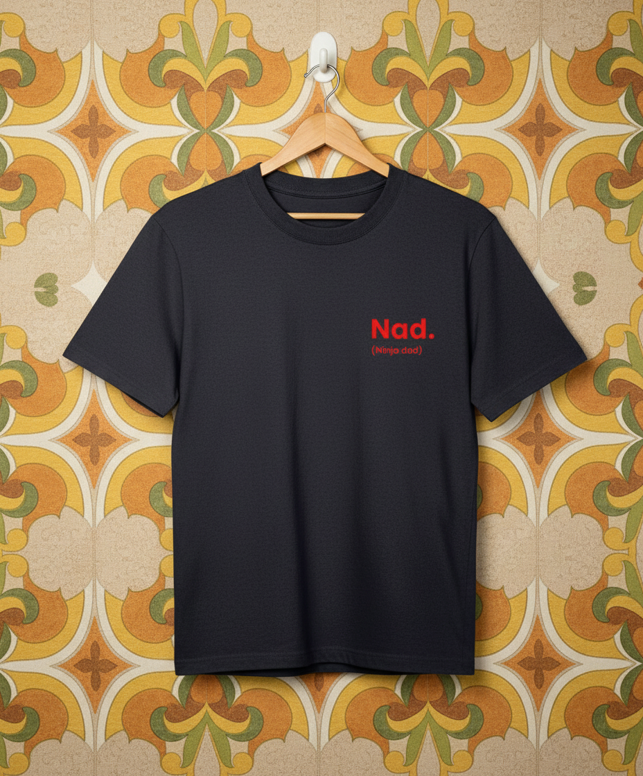 Dark navy T-shirt with red text 'Nad.' on a hanger against a patterned wall.