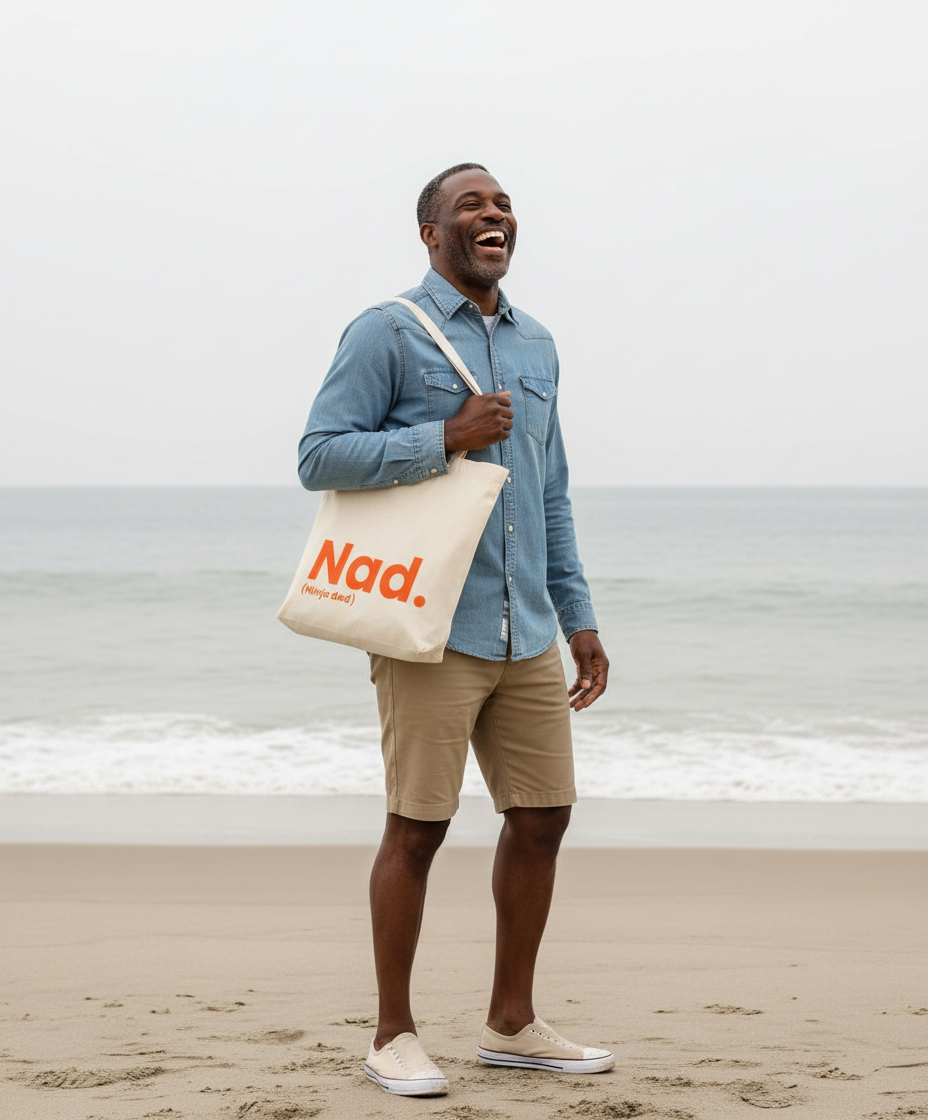 Man holding a tote bag with 'Nad' on it at the beach
