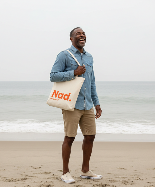 Man holding a tote bag with 'Nad' on it at the beach