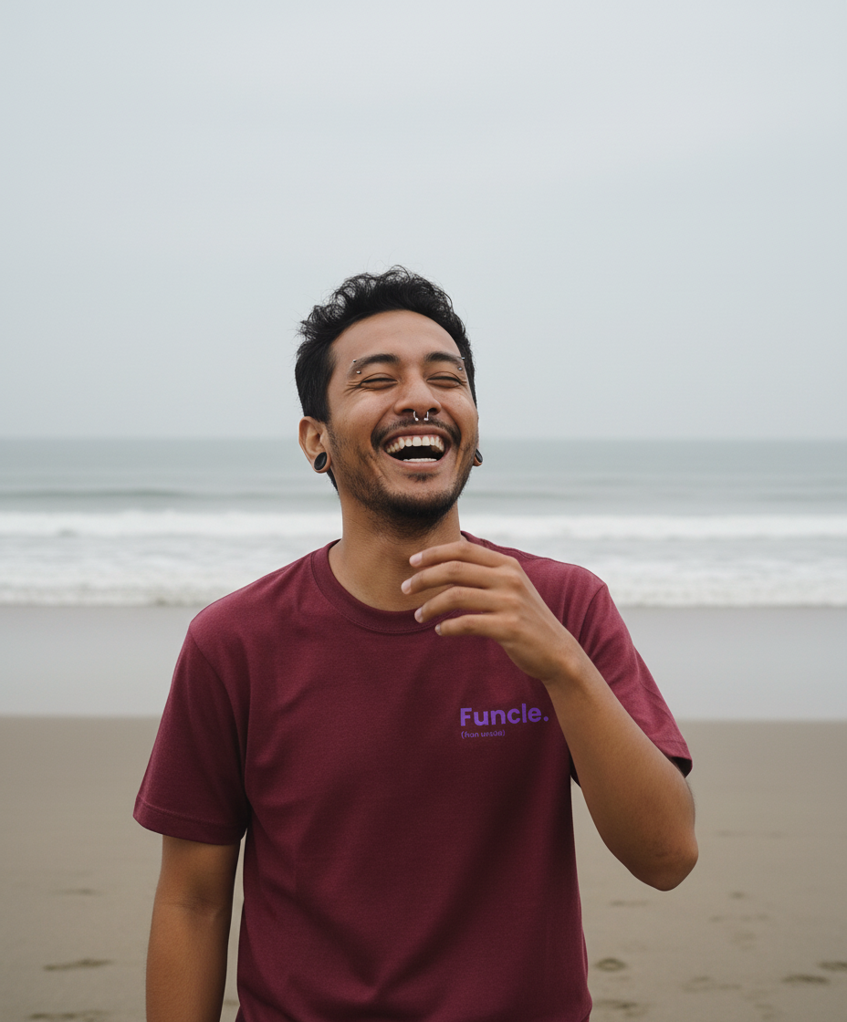 Man laughing on a beach wearing a maroon t-shirt with 'Funcle' logo