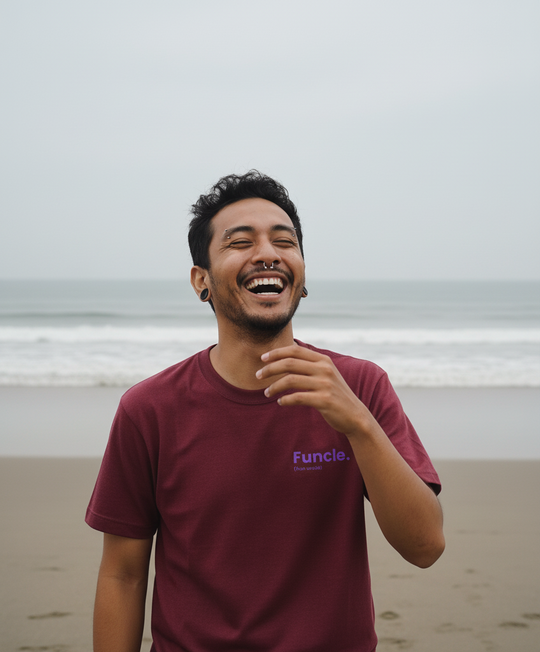 Man laughing on a beach wearing a maroon t-shirt with 'Funcle' logo
