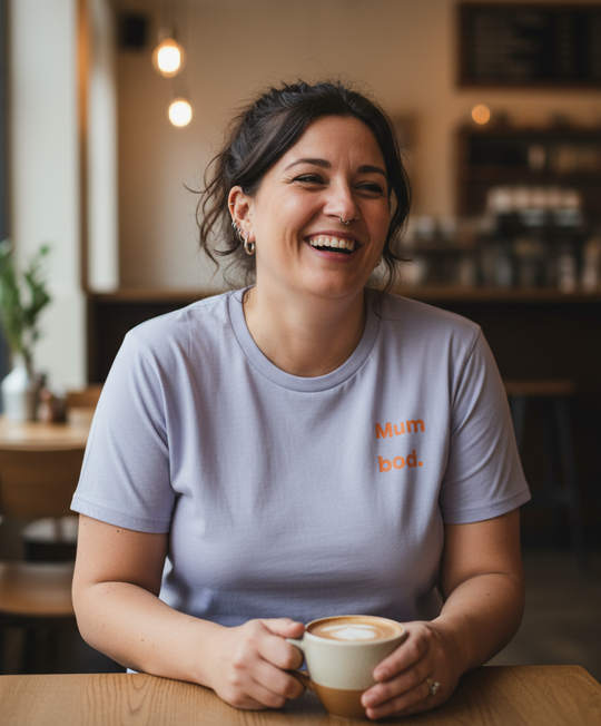 Woman in a casual setting holding a coffee cup, wearing a t-shirt with text.