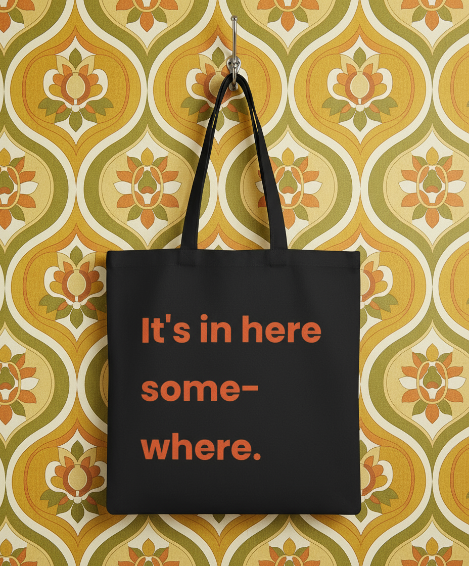 Black tote bag with red text on a patterned wall background
