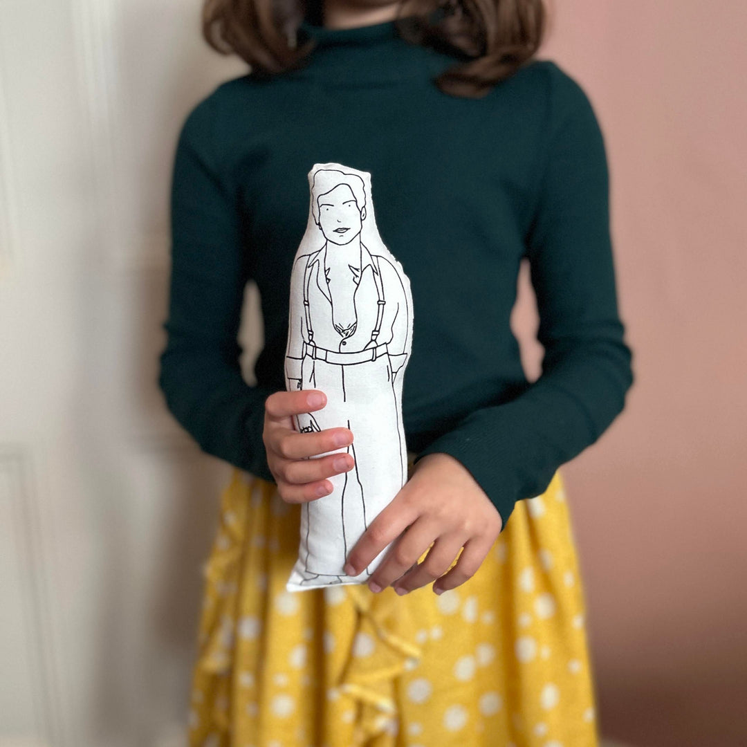 A child holding a screen printed doll cushion of Harry Styles