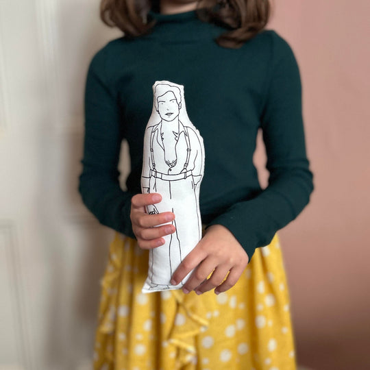 A child holding a screen printed doll cushion of Harry Styles