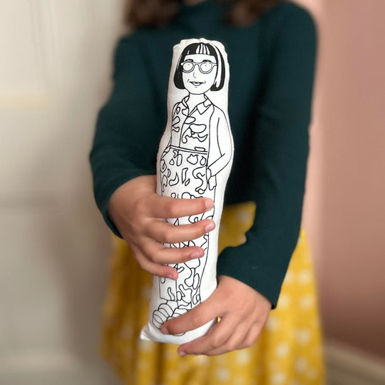 A child holding a black and white screen printed cushion doll featuring an illustrated design of Philippa Perry