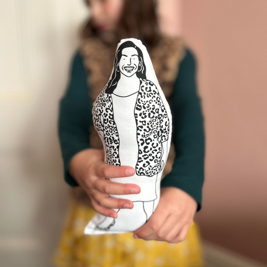 A child holding out the screen printed doll cushion of Allison Hammond