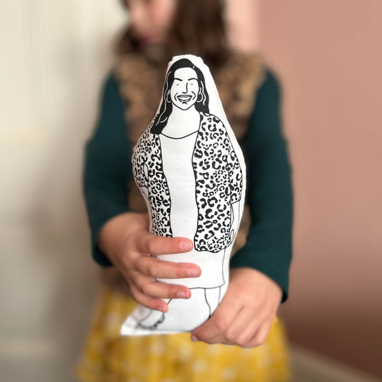 A child holding out the screen printed doll cushion of Allison Hammond