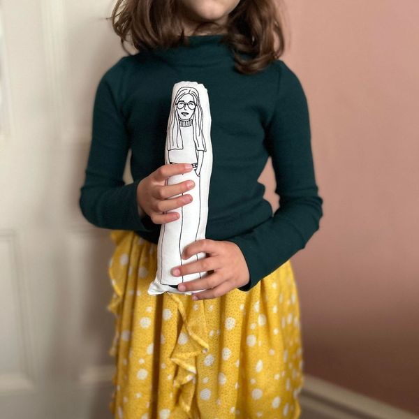 A child holding screen printed doll cushion of Gloria Steinem
