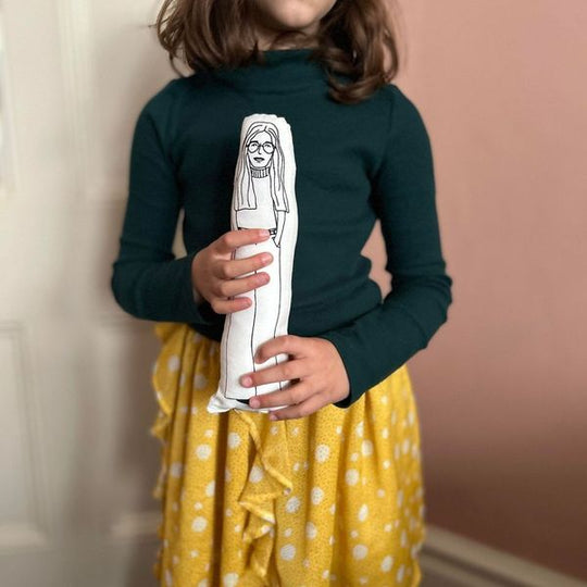 A child holding screen printed doll cushion of Gloria Steinem