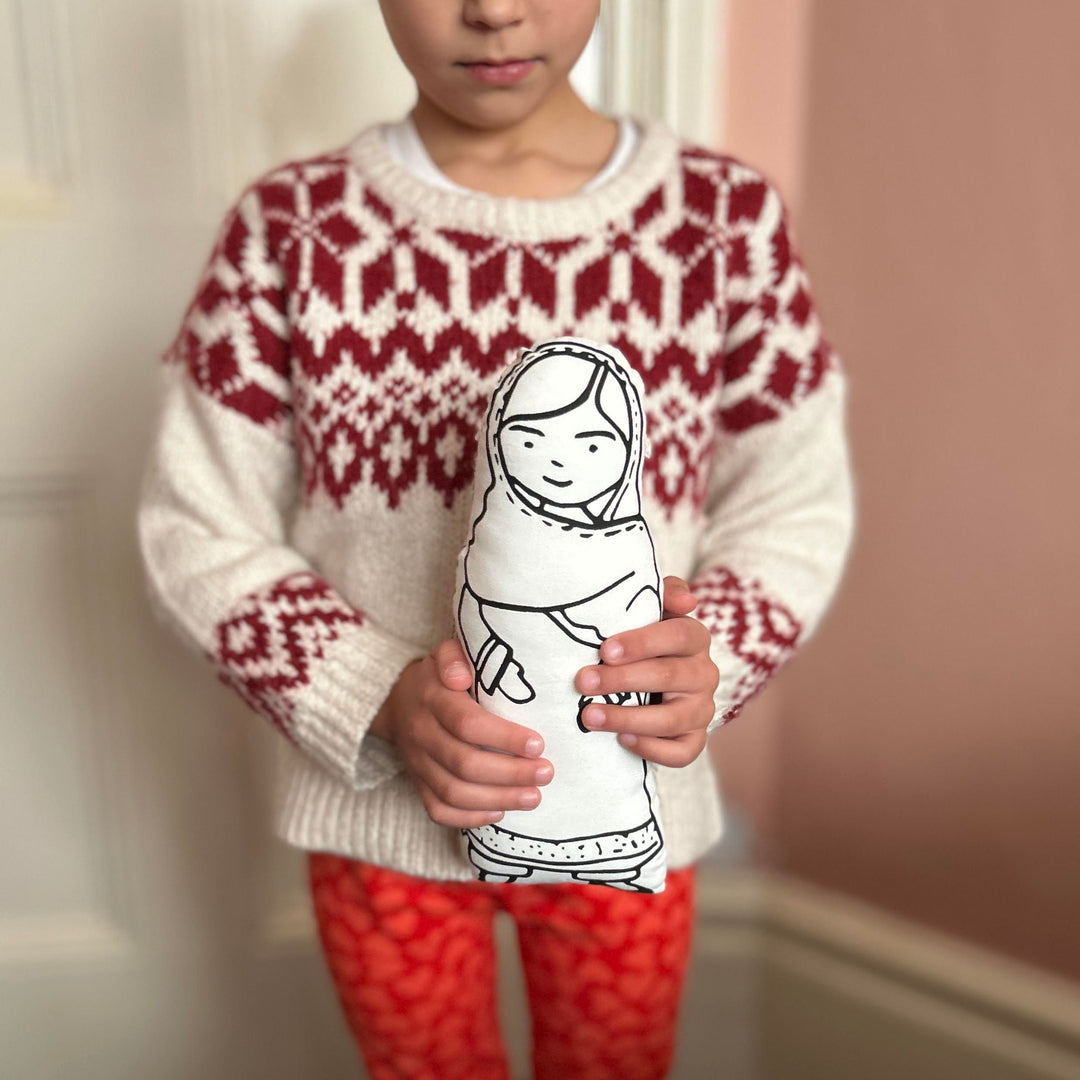 A child holding a screen printed doll cushion of Malala Yousafzai