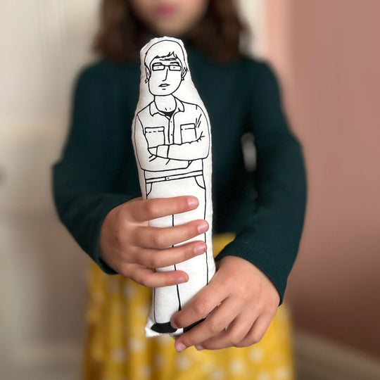 A child holding out the screen printed doll cushion of Louis Theroux