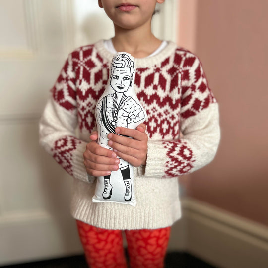 A child holding a black and white screen printed cushion doll depicting a stylised version of Vivienne Westwood.