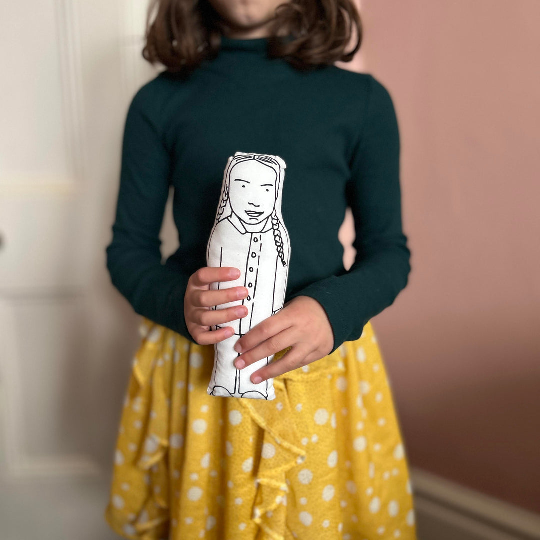 A child holding a screen printed Greta Thunberg doll cushion