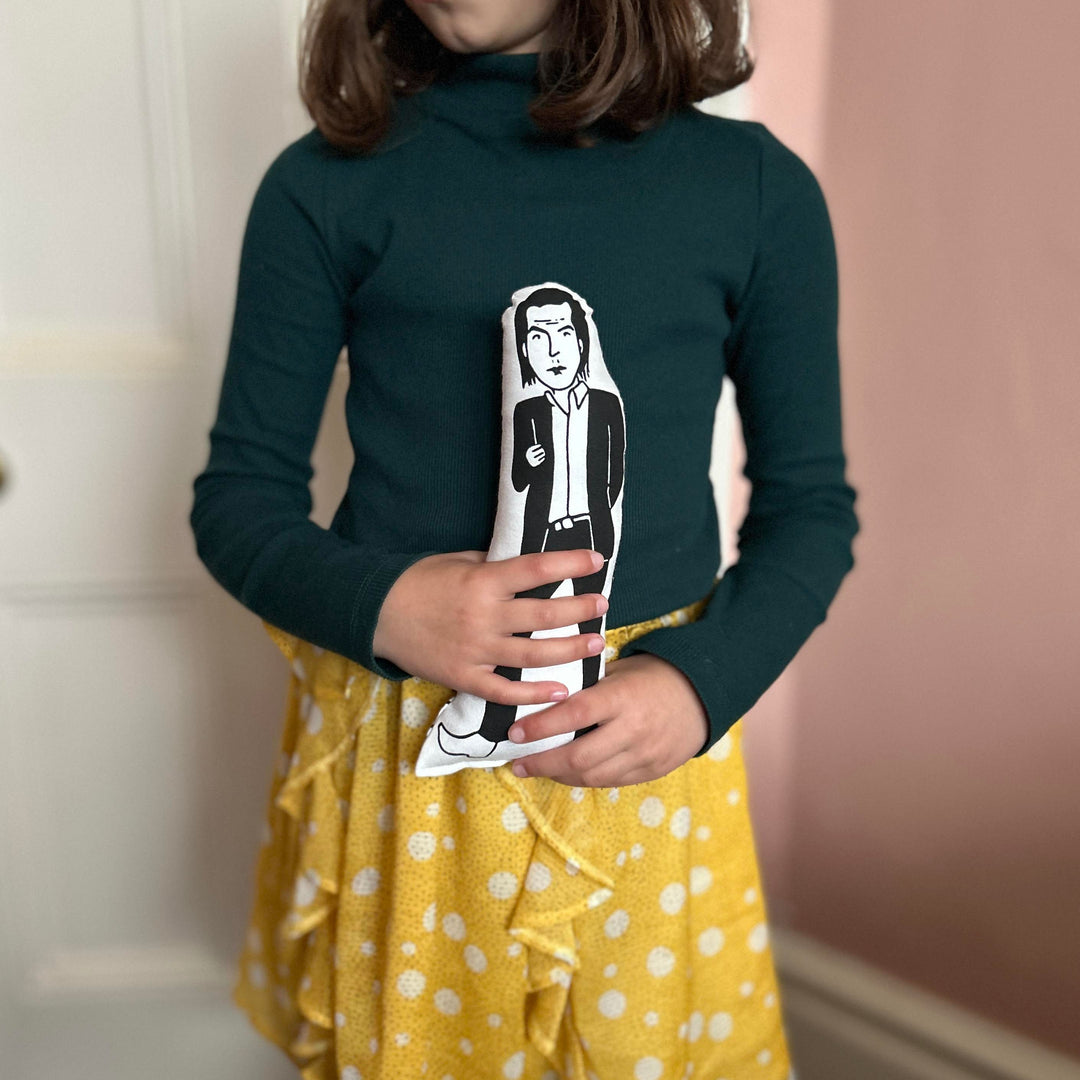 A child holding a screen printed doll cushion of Nick Cave