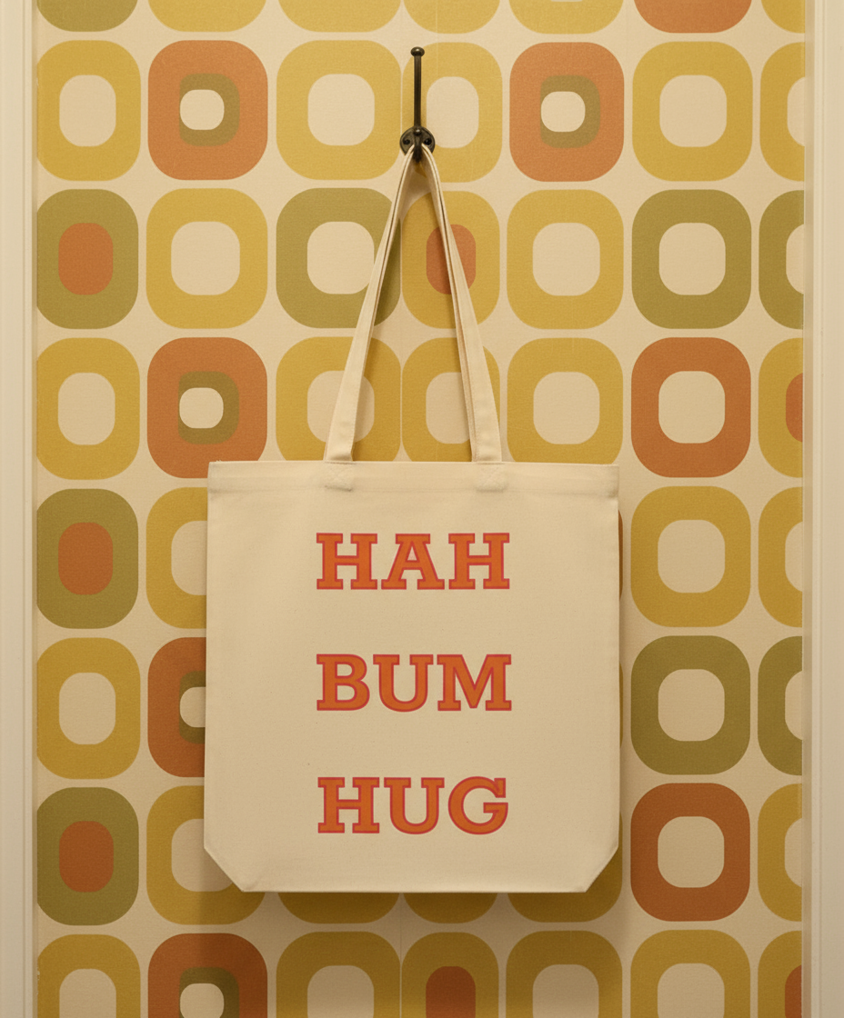 Tote bag with 'HAH BUM HUG' text hanging on a wall with a patterned background