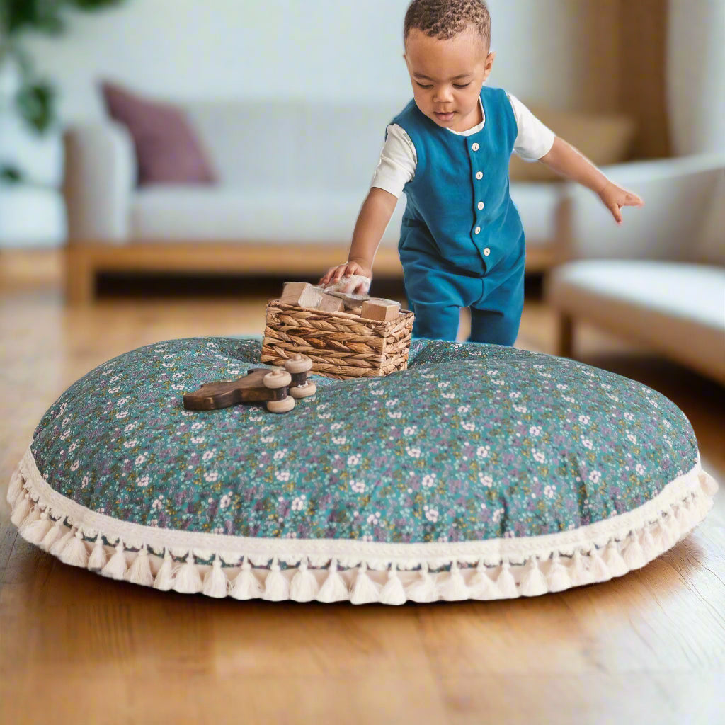 Child playing with wooden toys on a large round floral-patterned floor cushion