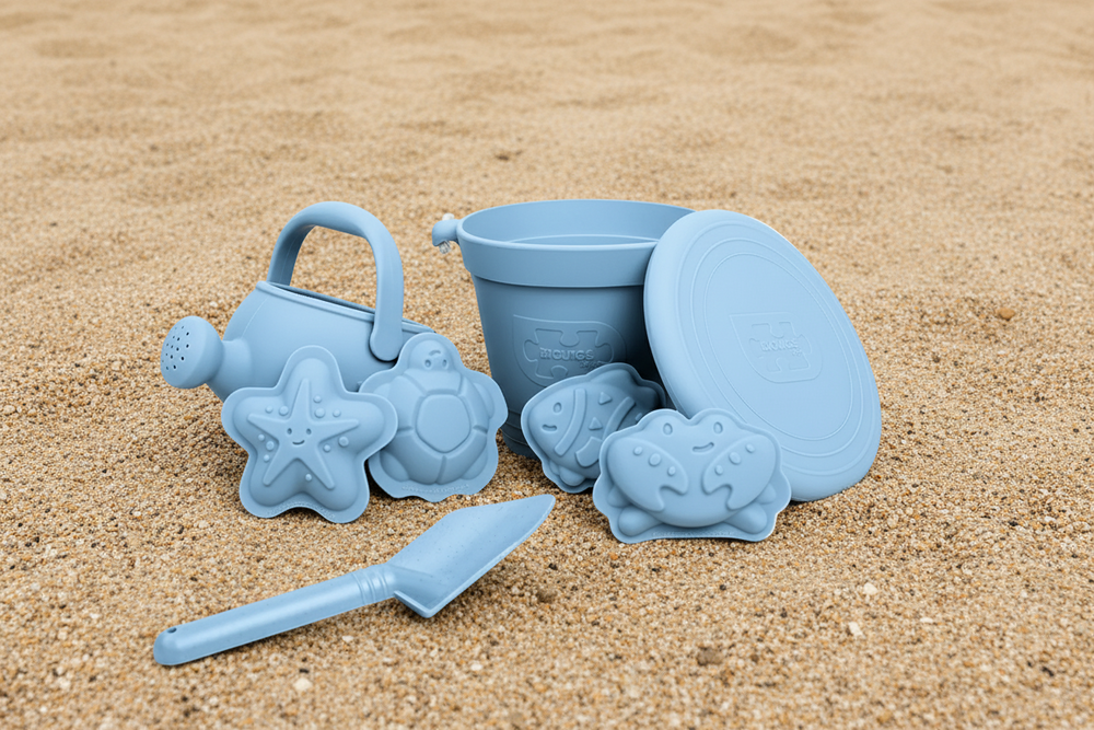 Set of blue sand toys including a bucket, spade, and molds on a white background