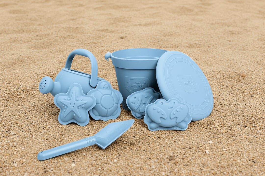 Set of blue sand toys including a bucket, spade, and molds on a white background