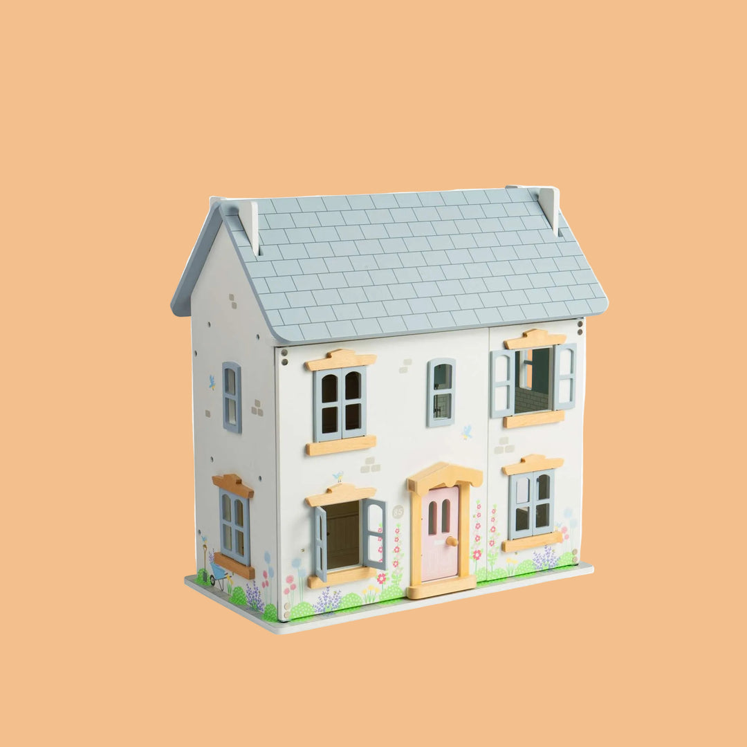 Wooden dollhouse with a light blue roof on a white background