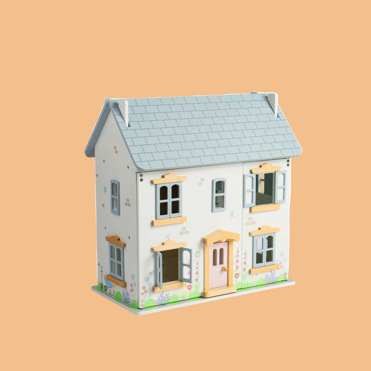 Wooden dollhouse with a light blue roof on a white background