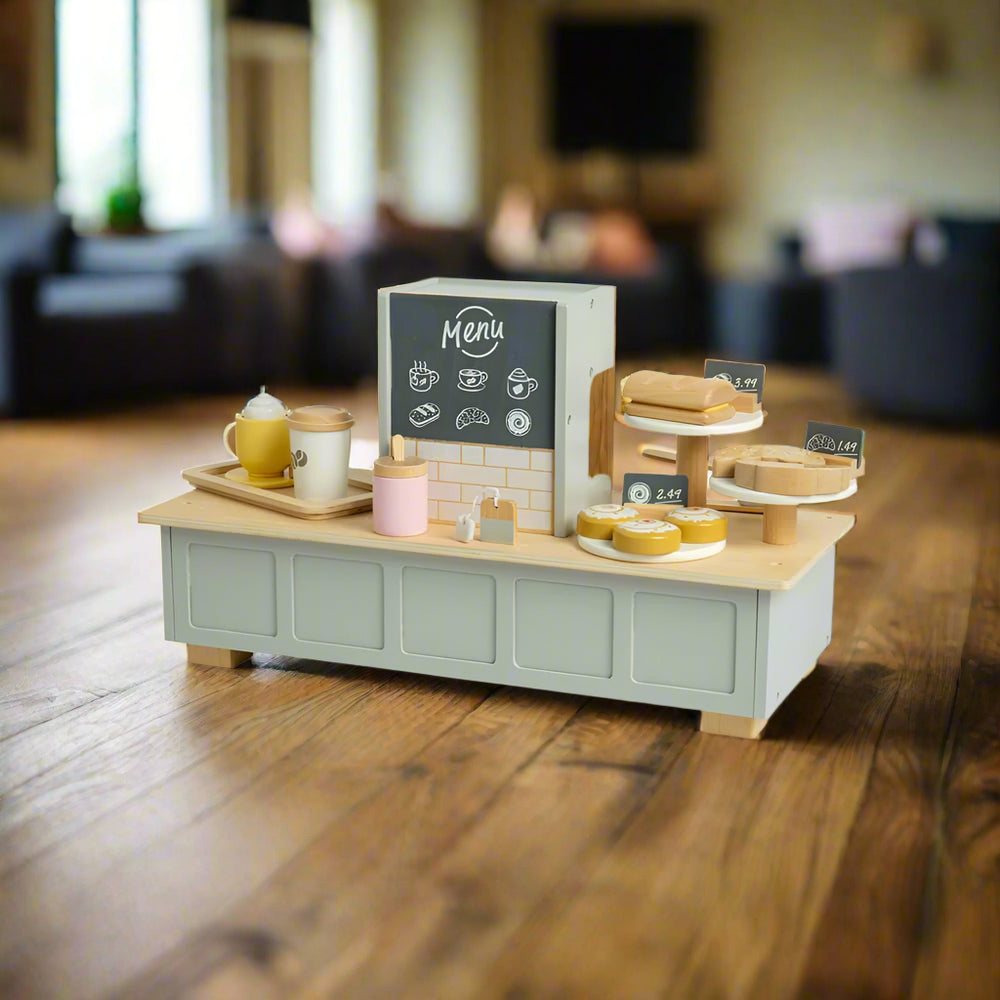 Shows the toy coffee machine/cafe from the back, as the customers would see it - with a chalkboard menu and showing the plates of cakes with price labels