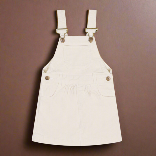 White corduroy dress with two pockets either side of the dress and also a central pocket on the chest, and brass buttons 