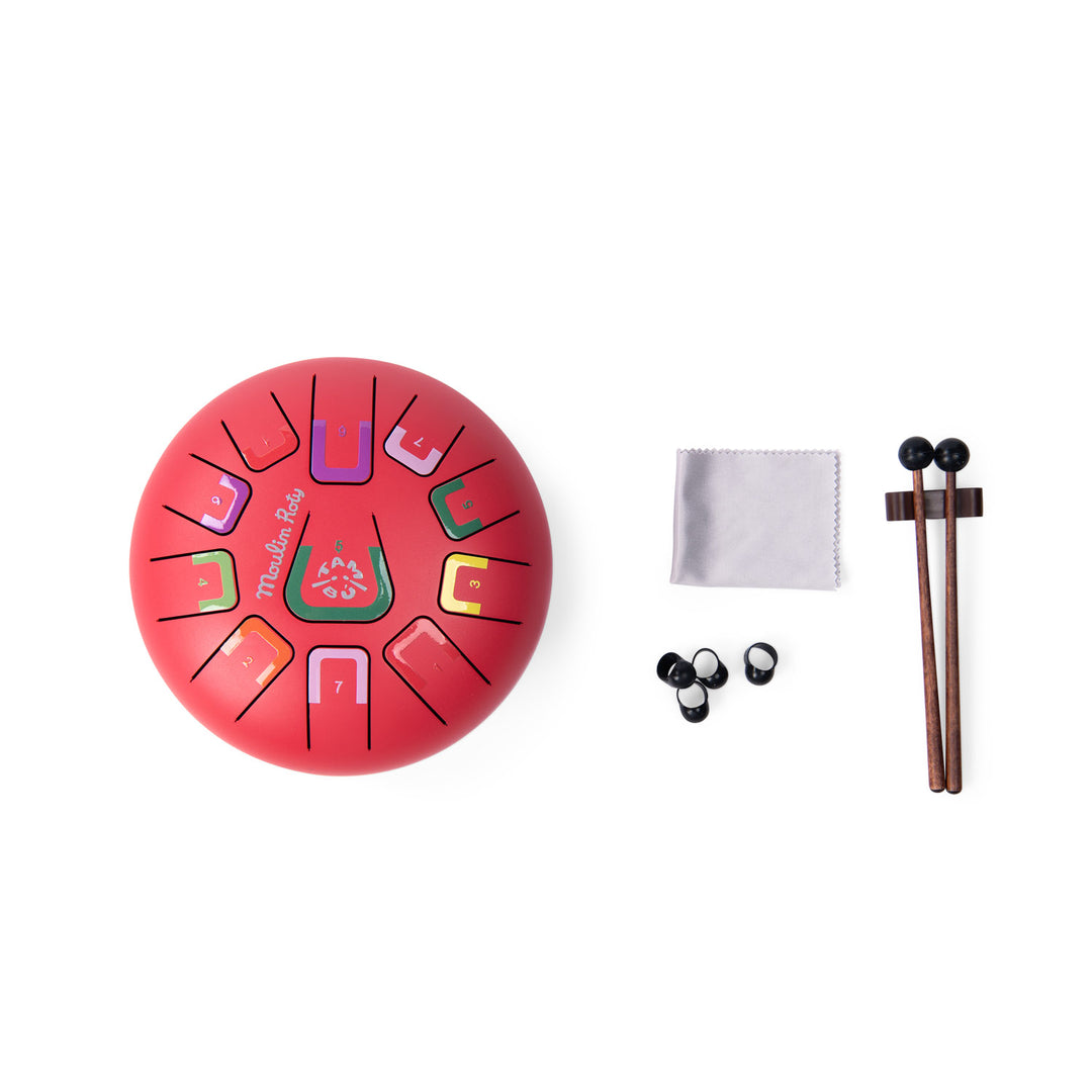 Red metal tongue drum instrument with colour coded notes, two drumsticks and four finger tip accessories, and a cleaning cloth