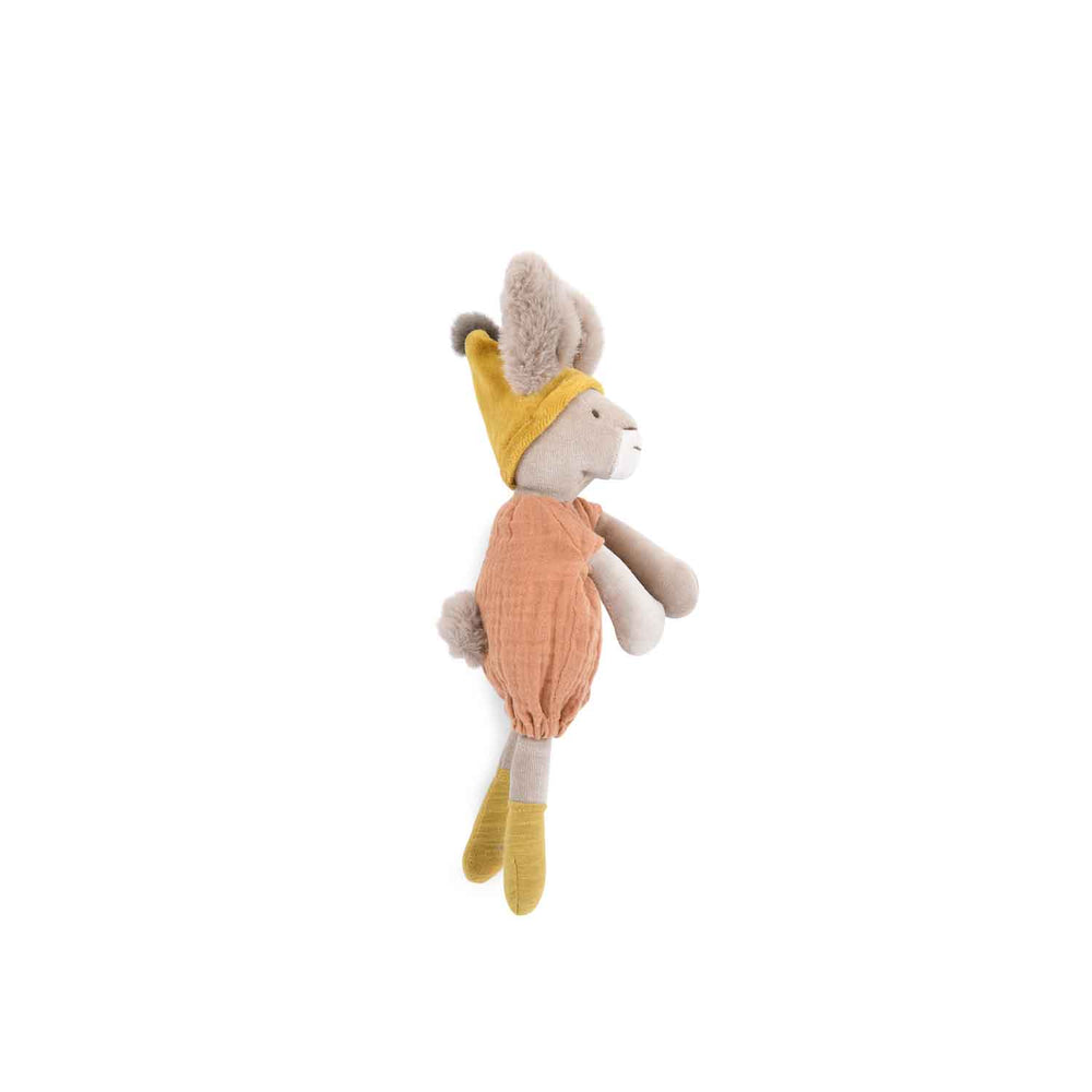 Stuffed toy abbit facing the side, showing it's fluffy tail poking out of the peach romper and detail of the hat which is pointed with a fluffy bobble