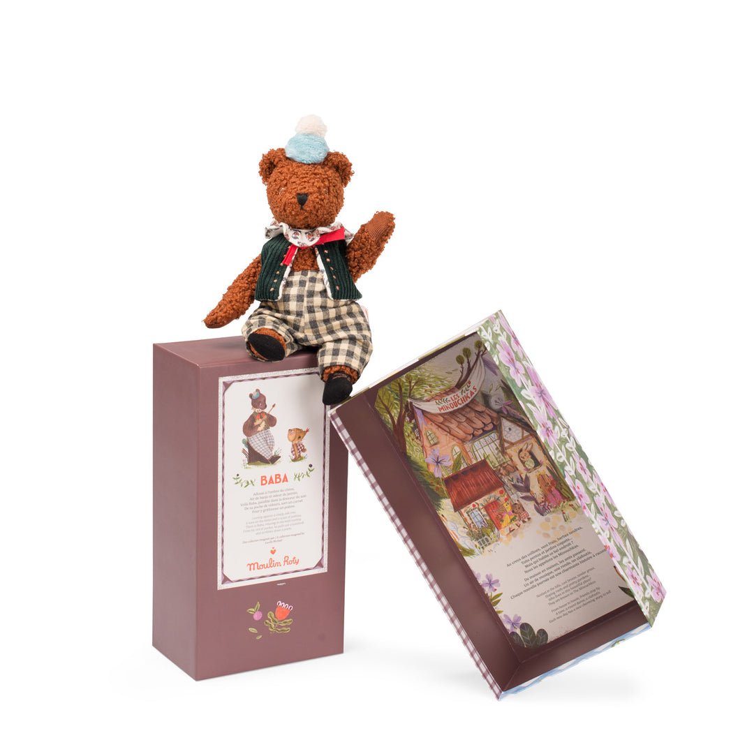 Teddy bear sitting on decorative packaging with arm raised