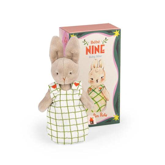 Plush rabbit toy in a white checked sleepsack with decorative packaging box behind labeled 'Bèbé Nine'
