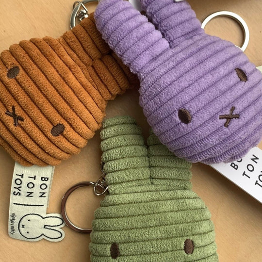 Three colourful keyrings shaped like bunny heads on a wooden surface with 'Bon Ton Toys' branding.
