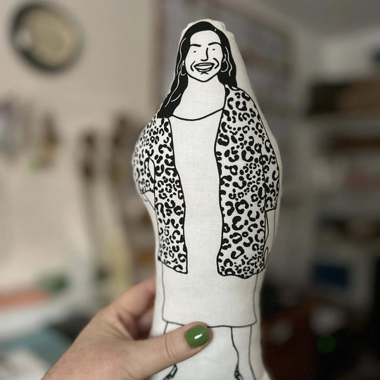 Hand holiding screen printed doll cushion of Allison Hammond against an out of focus background
