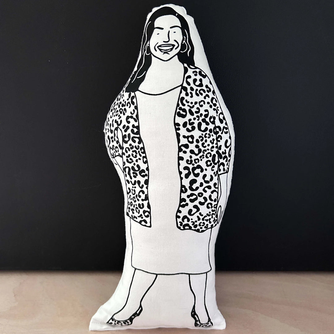 Screen printed doll cushion with white fabric and black illustration depicting TV presenter Allison Hammond wearing a dress and a leopard print cardigan with hoop earrings