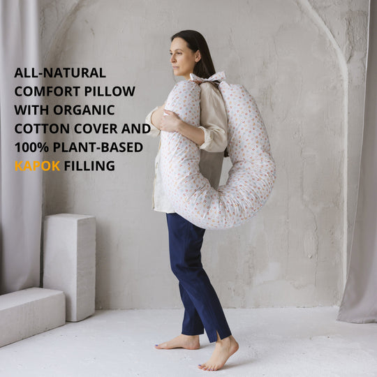 Person holding a large, round, white pillow with text about its natural and organic features.