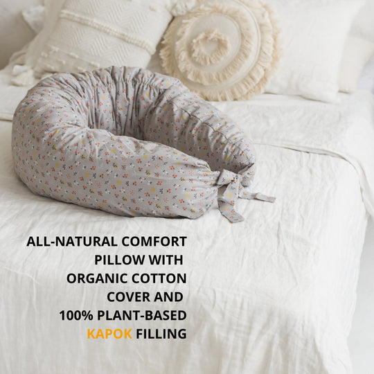 Floral-patterned all-natural comfort pillow on a bed with text about organic cotton cover and plant-based kapok filling.