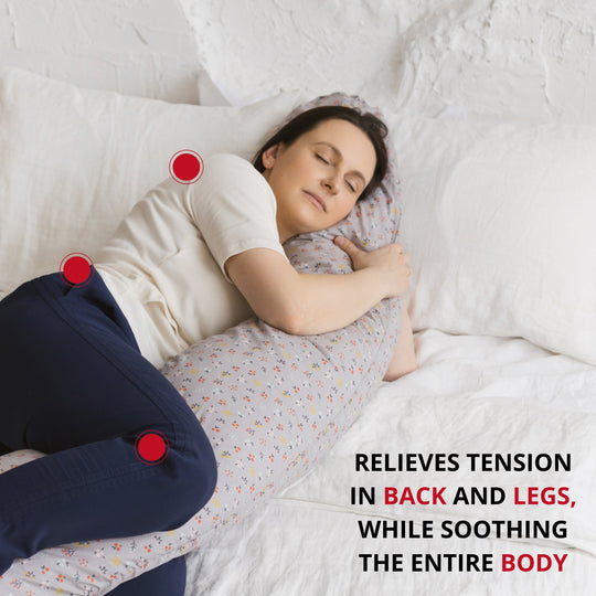 Woman lying on a bed hugging the support pillow, with text about it relieving tension in back and legs while soothing the entire body