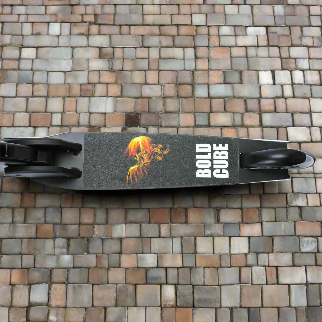 Close up birds eye view looking down at the tread of the scooter, showing a black deck with a fire design and branding 'Bold Cube' written on it
