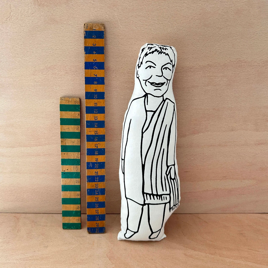 Screen printed doll cushion of Dame Judi Dench next to two wooden rules on a wooden background