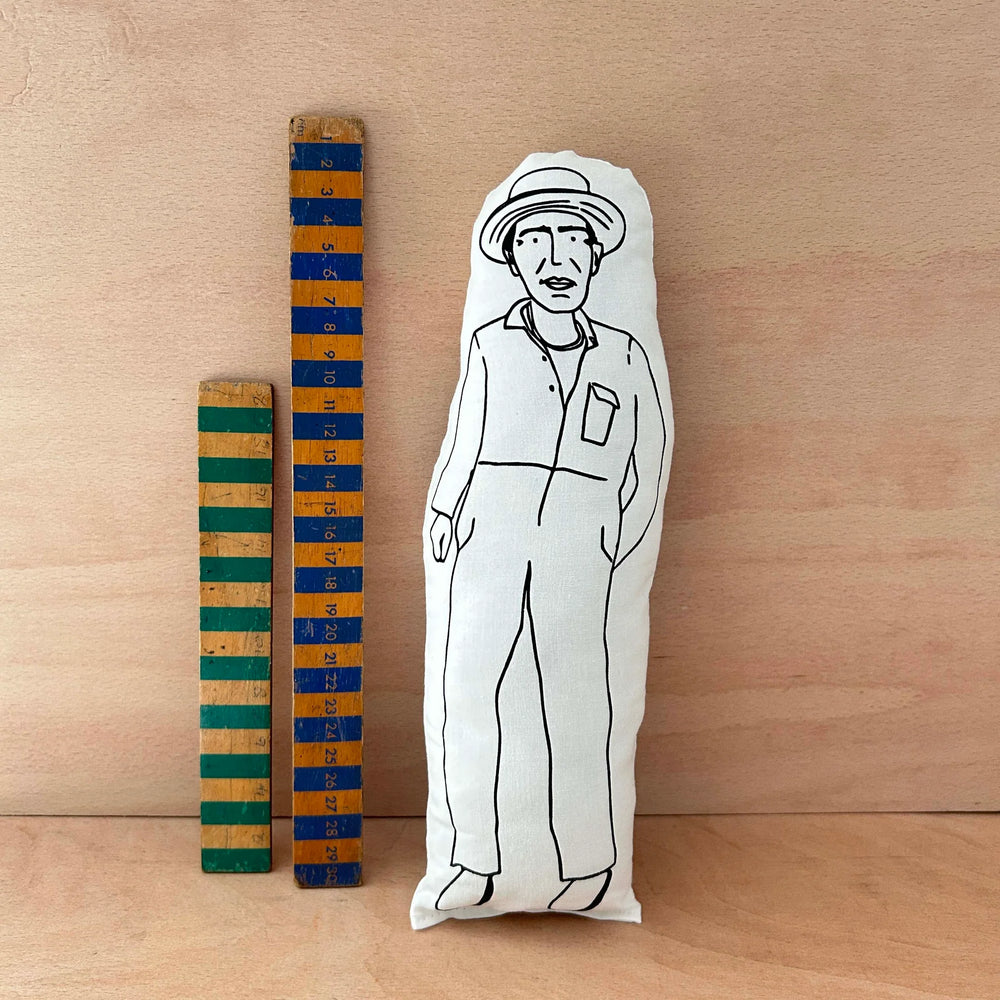 Screen printed doll cushion of Derek Jarman next to two wooden rulers on a wooden background