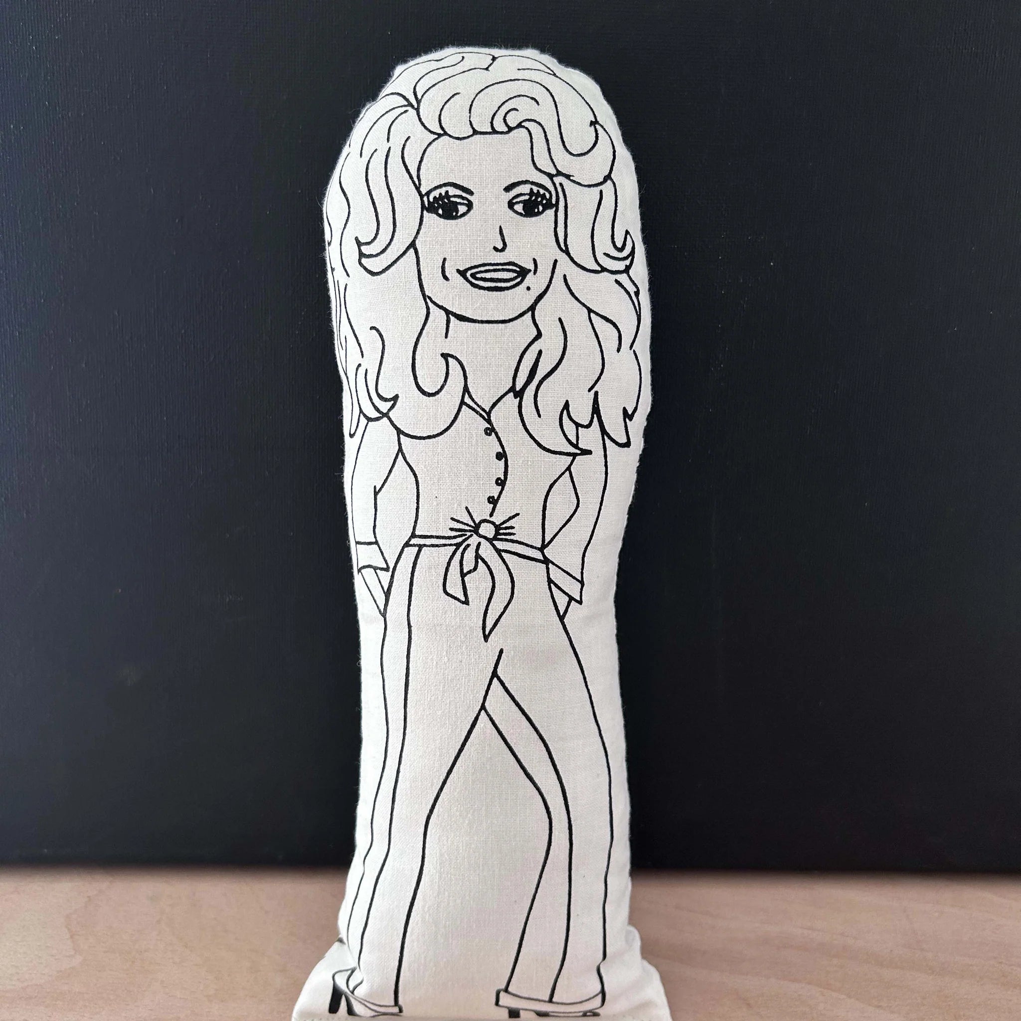 White plush toy with black outline of a person on a dark background