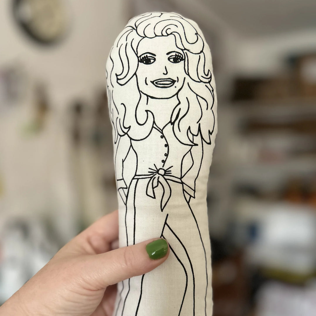 Hand holding a plush toy with a black and white outline of a person on a beige background.