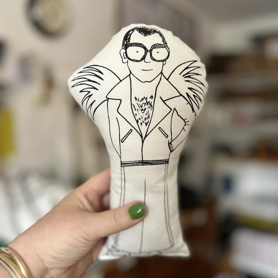 Hand holding the doll with a black and white illustration of a person wearing glasses and a suit.